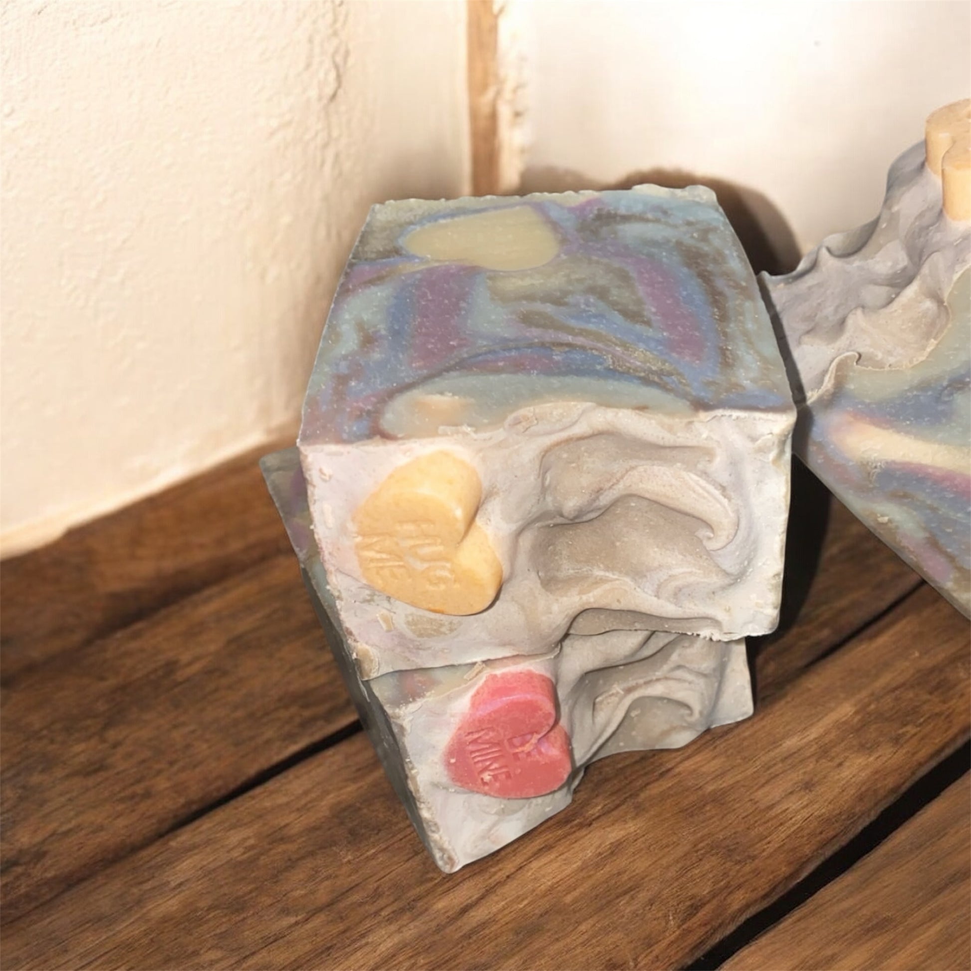 Two soap with vibrant colors sitting on a wooden bench 