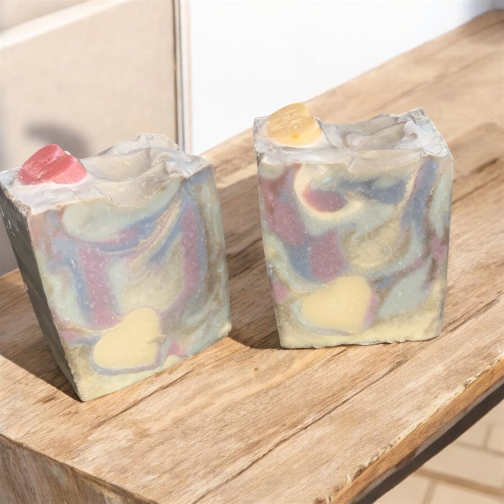 Two soap with vibrant colors sitting on a wooden bench 