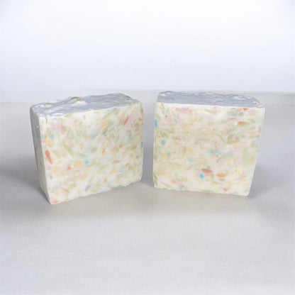 Two blocks of white soap with colorful specks on a light gray background