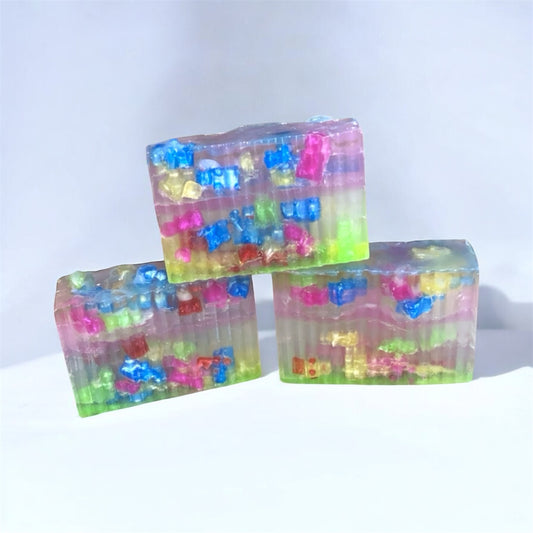 Three colorful soap bars with embedded gummy bear shapes on a white background