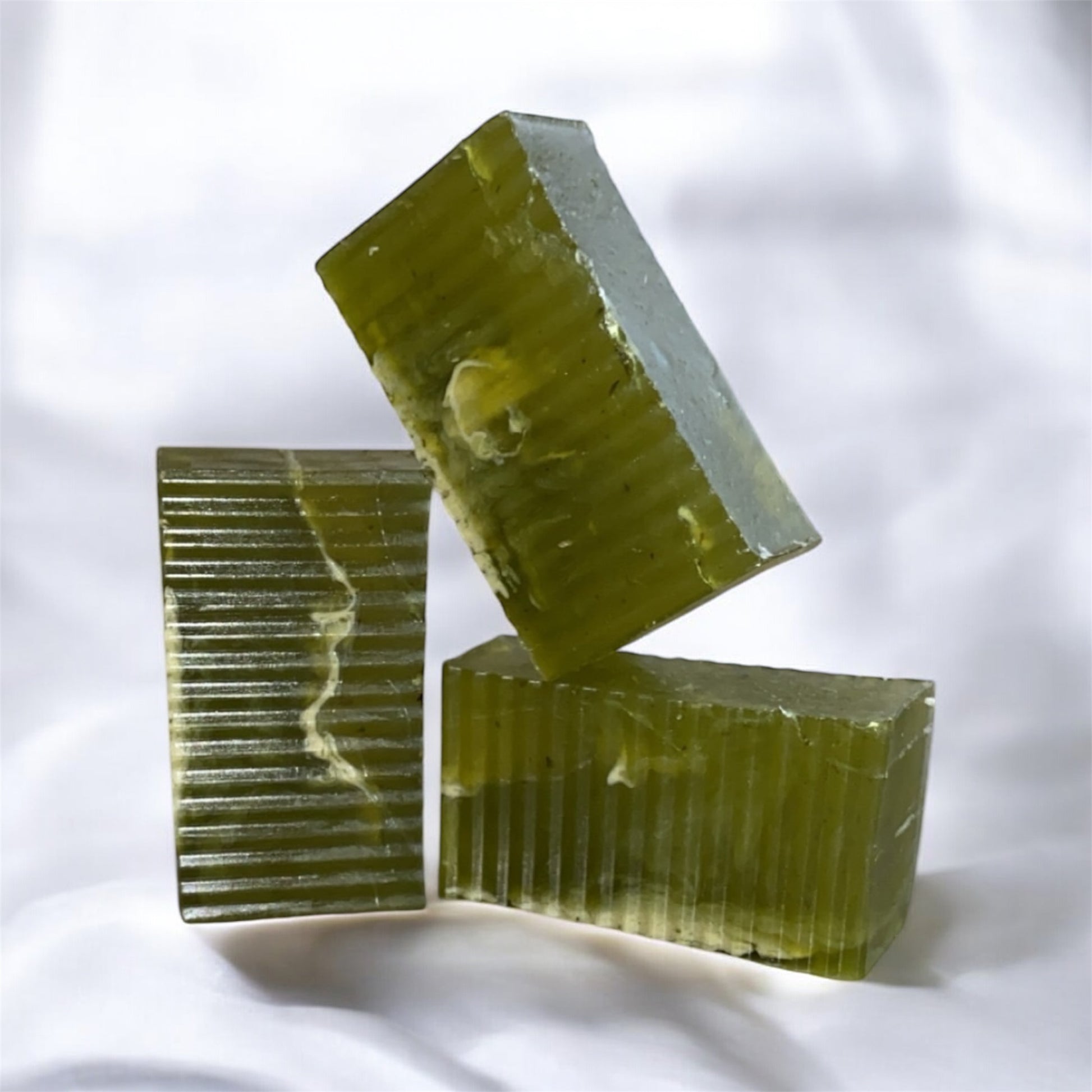 Three green soap bars stacked on a white background
