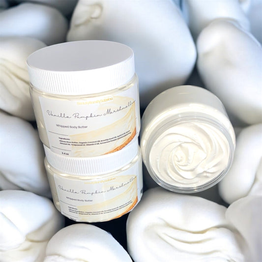 Jar of whipped body butter with a swirl of cream on top, surrounded by more cream.