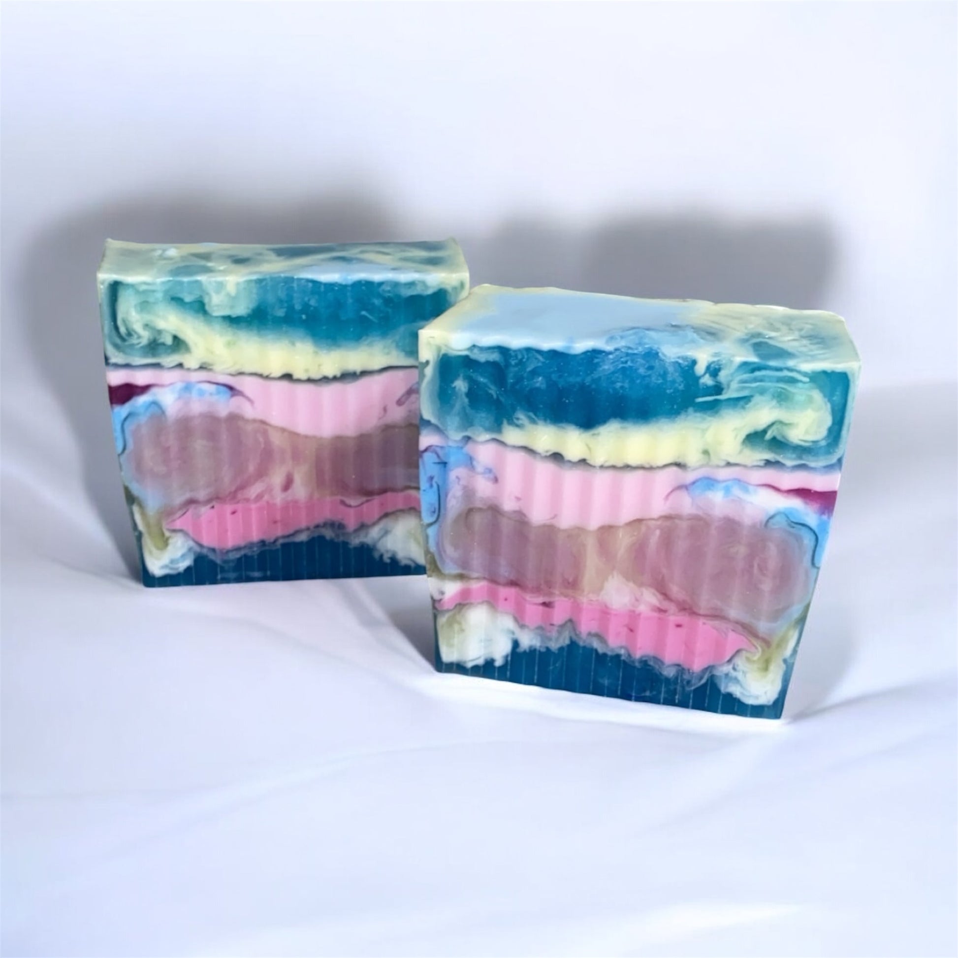 Two colorful soap bars with a gradient of blue, pink, and green on a white background.