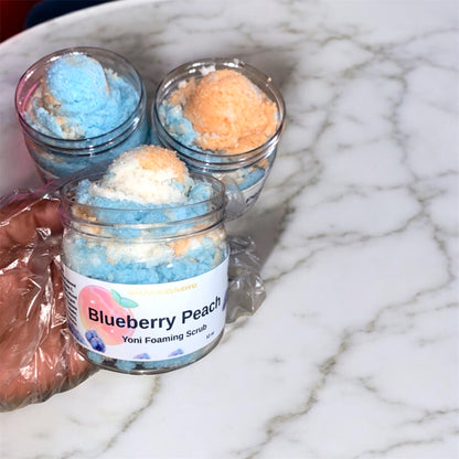 Yoni foaming scrub in jars with visible branding on a marble surface with hand hold a jar
