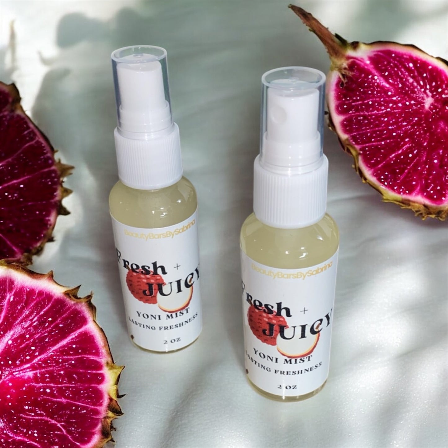 Two bottles of 'Fresh Juicy' yoni mist with dragon fruit on a white background