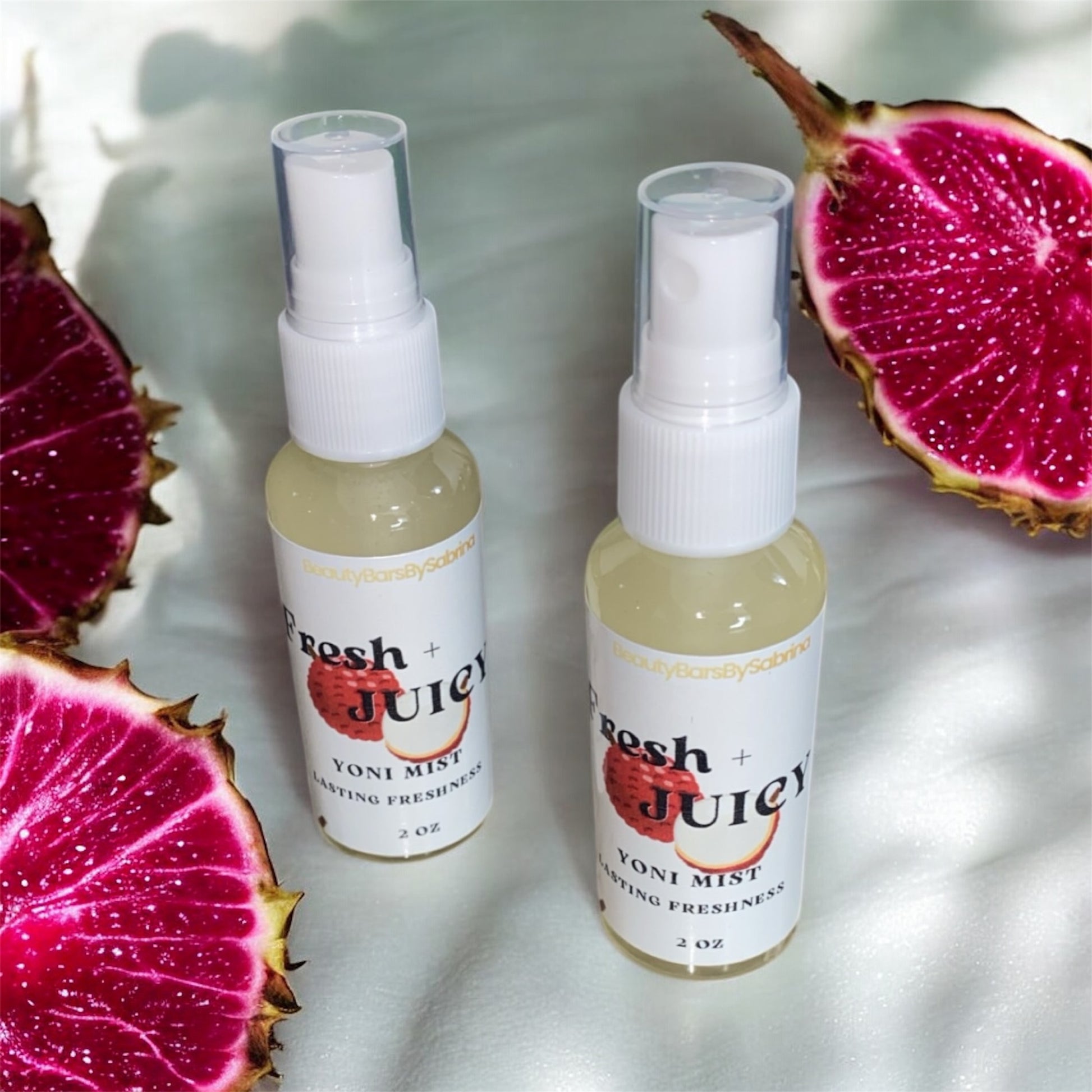 Two bottles of 'Fresh Juicy' yoni mist with dragon fruit on a white background