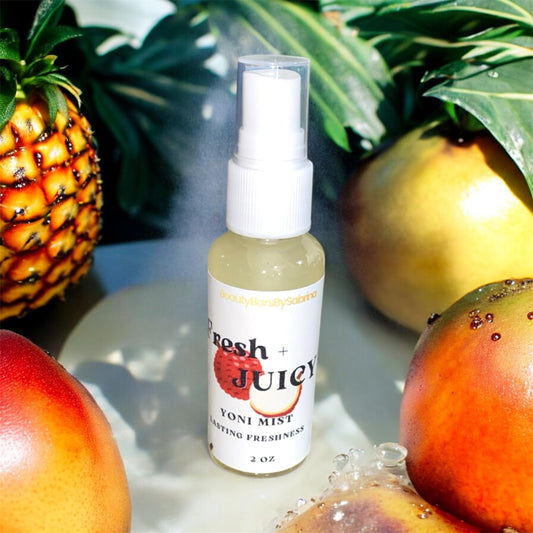 Yoni mist spray bottle labeled 'Fresh + Juicy' surrounded by fruits on a light background