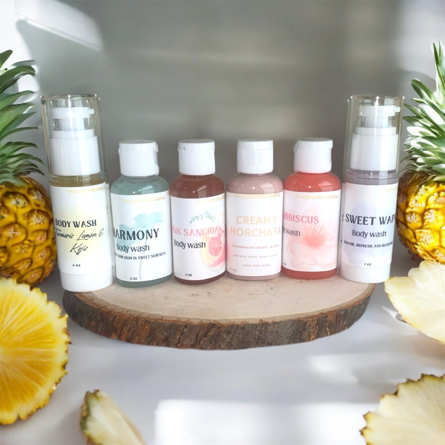 Row of body wash bottles on a wooden surface with pineapples around