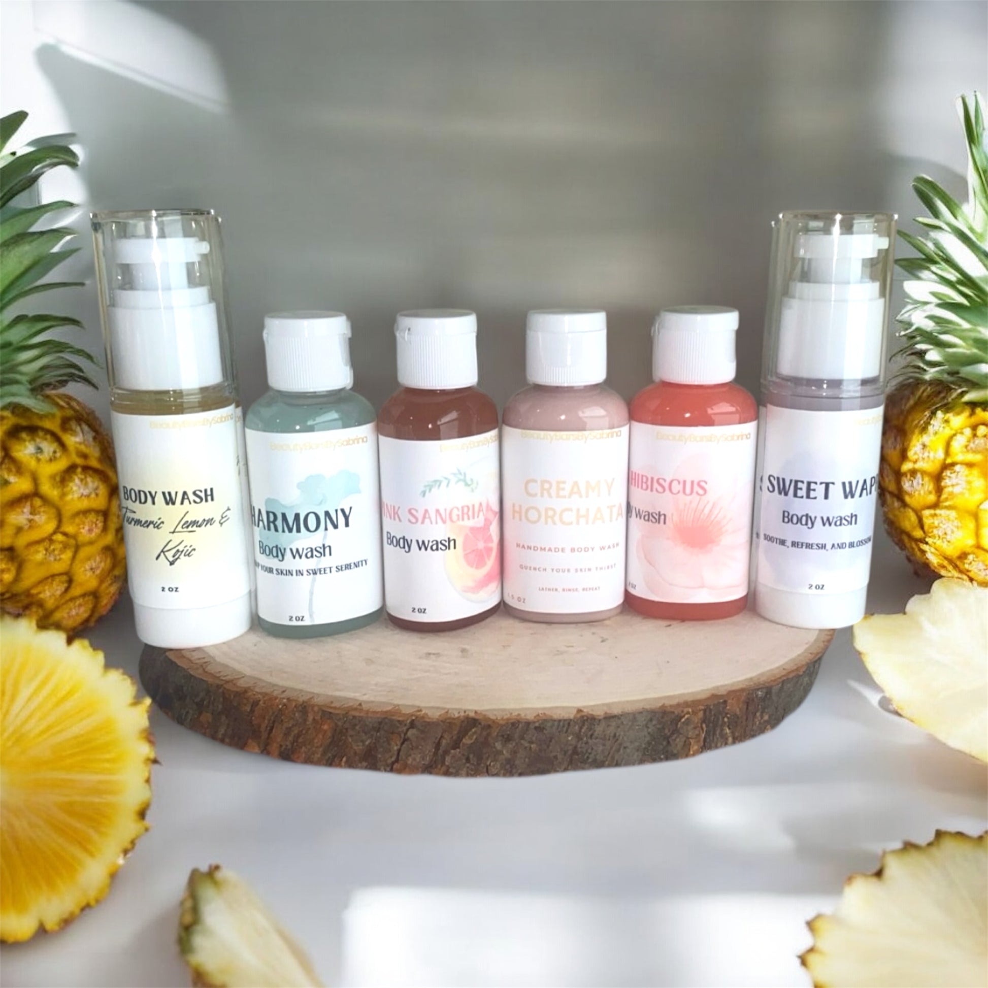 Row of body wash bottles on a wooden surface with pineapples around