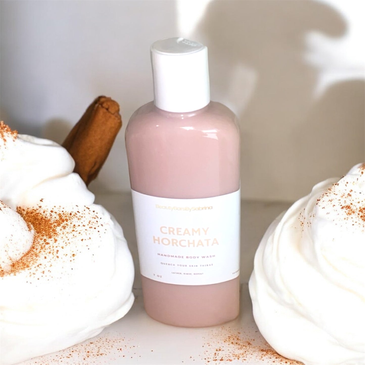 Bottle of body wash with whipped cream and cinnamon background 