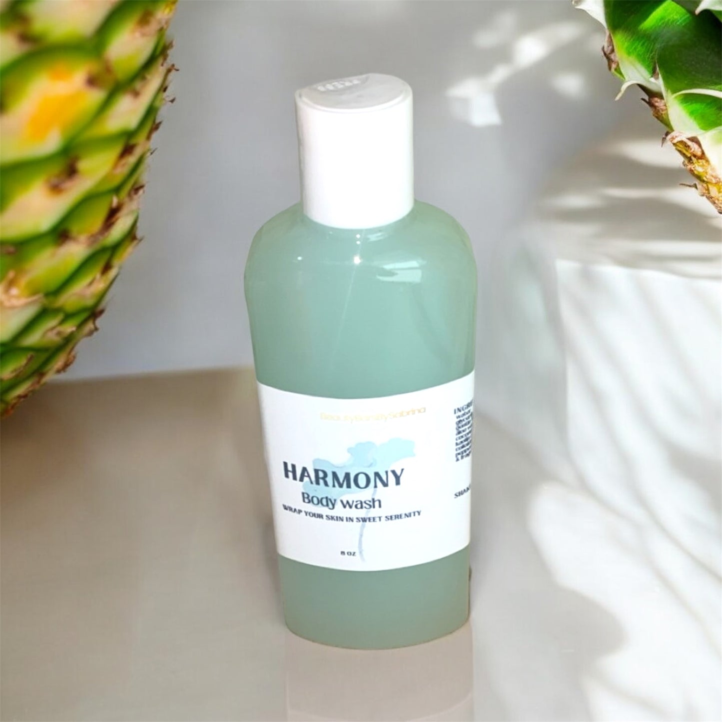 Bottle of Harmony body wash with a pineapple in the background