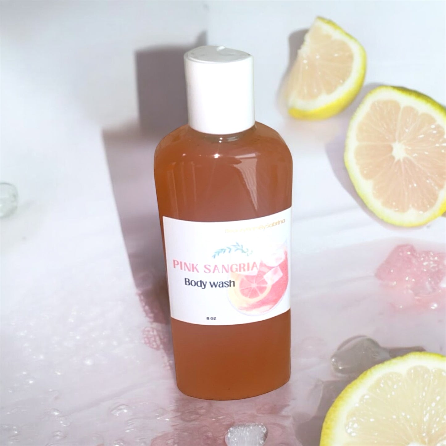 Bottle of Pink Sangria body wash with lemons and bubbles on a white background