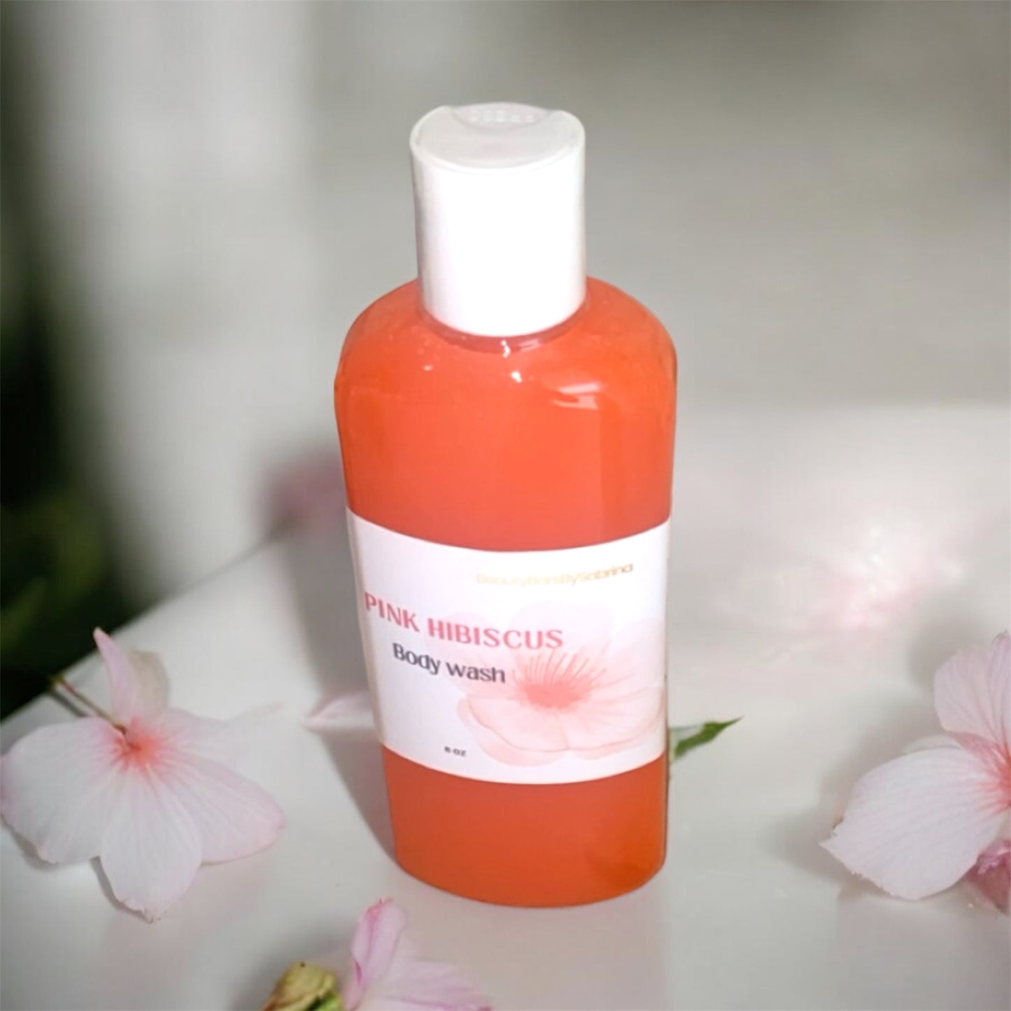 Bottle of Pink Hibiscus body wash with flowers in the background