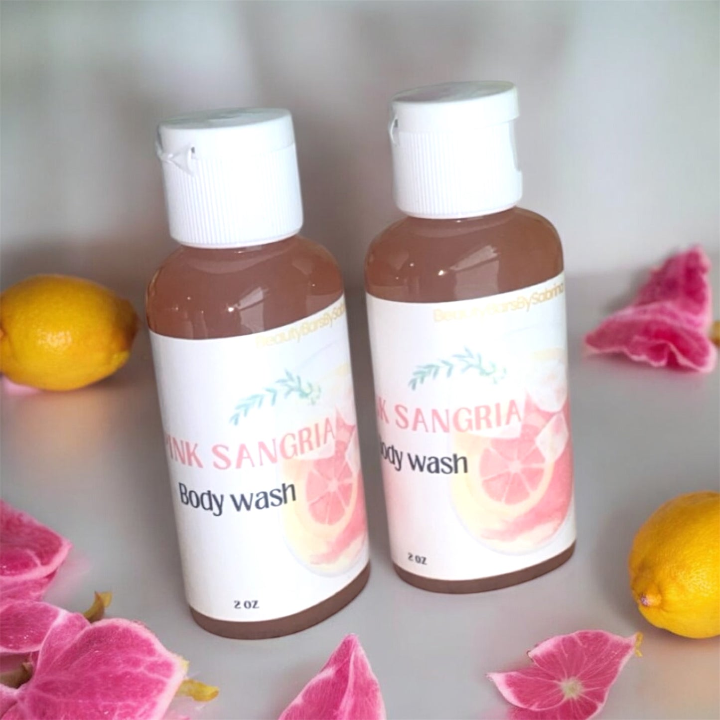 Two bottles of 'Pink Sangria' body wash with floral and fruit elements on a light background.
