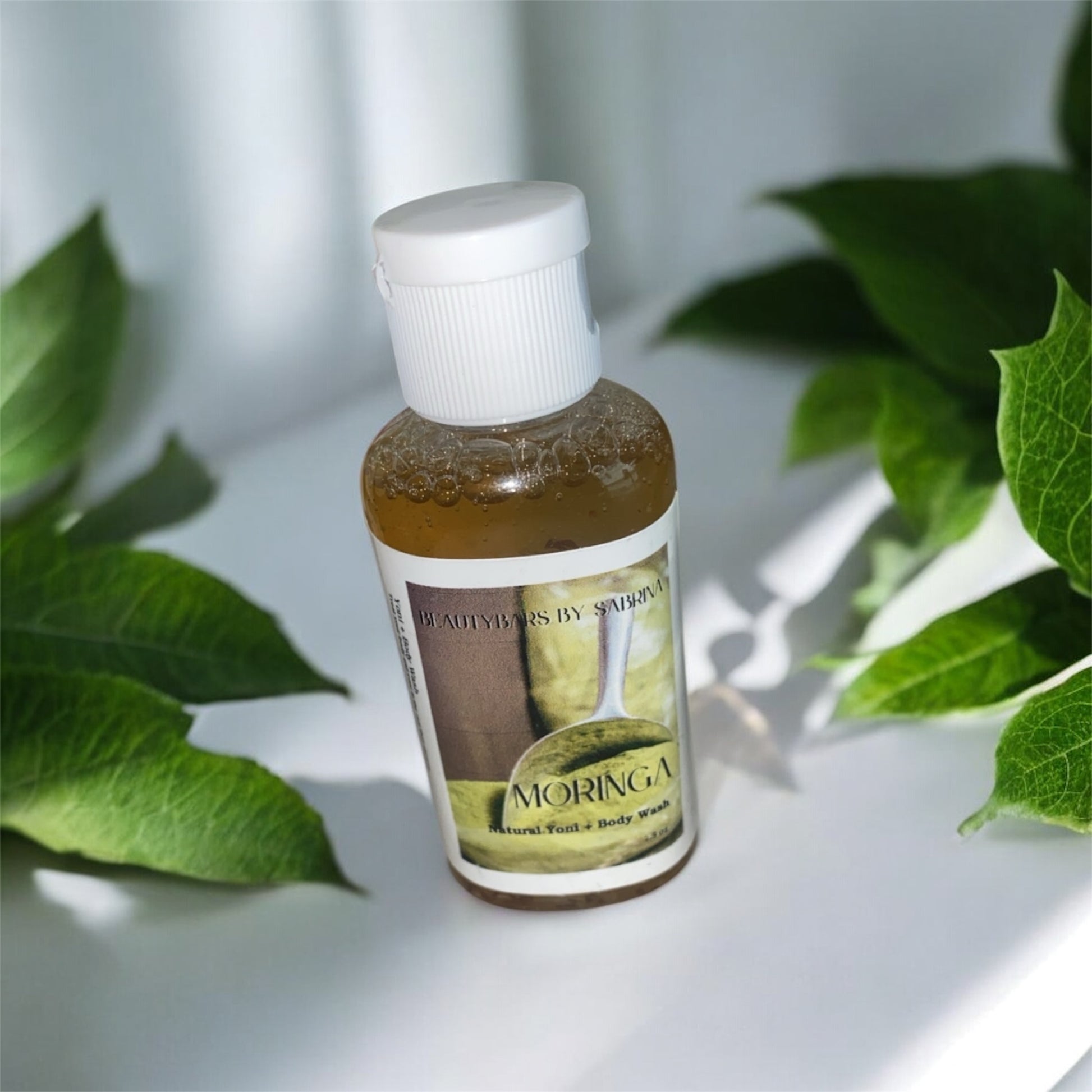 Bottle of Moringa product with green leaves in the background