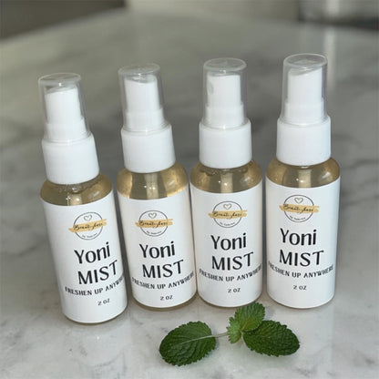 Four bottles of Yoni Mist on a marble surface with mint leaves.
