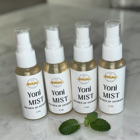 Four bottles of Yoni Mist on a marble surface with mint leaves.