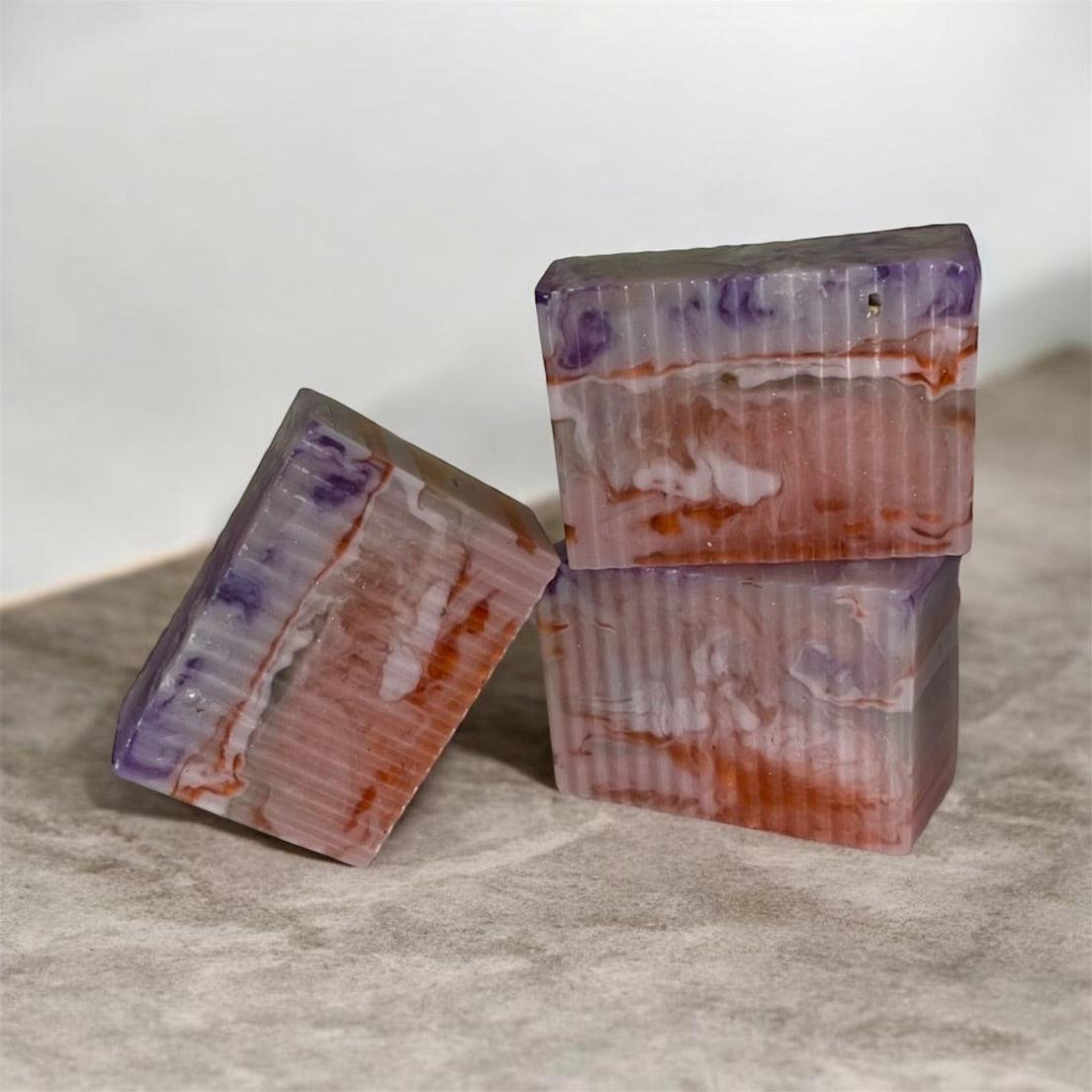Three bars of layered soap on a marble surface with a neutral background