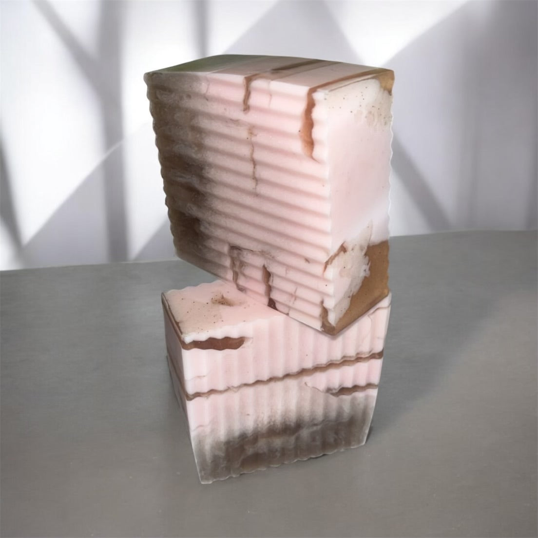 2 pink and brown soap stacked with layered design on a gray surface