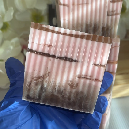 Have holding a pink and brown soap with flower background 