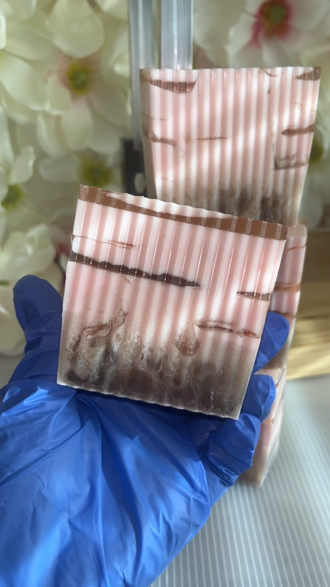 Have holding a pink and brown soap with flower background 