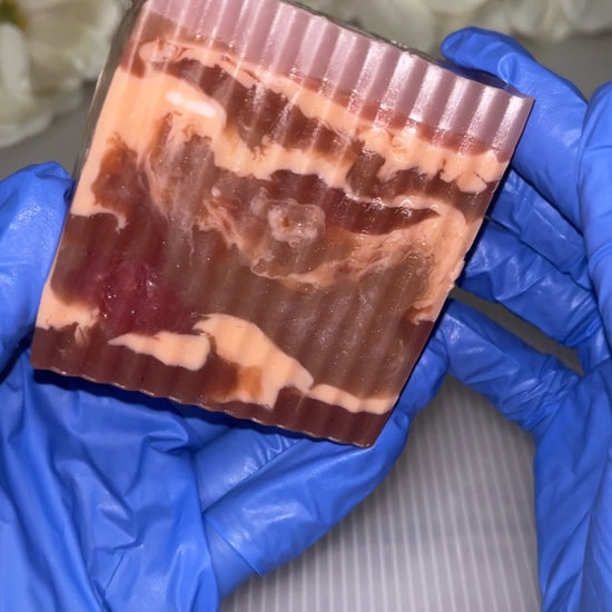 Hand with blue gloves holding a marble colored soap.