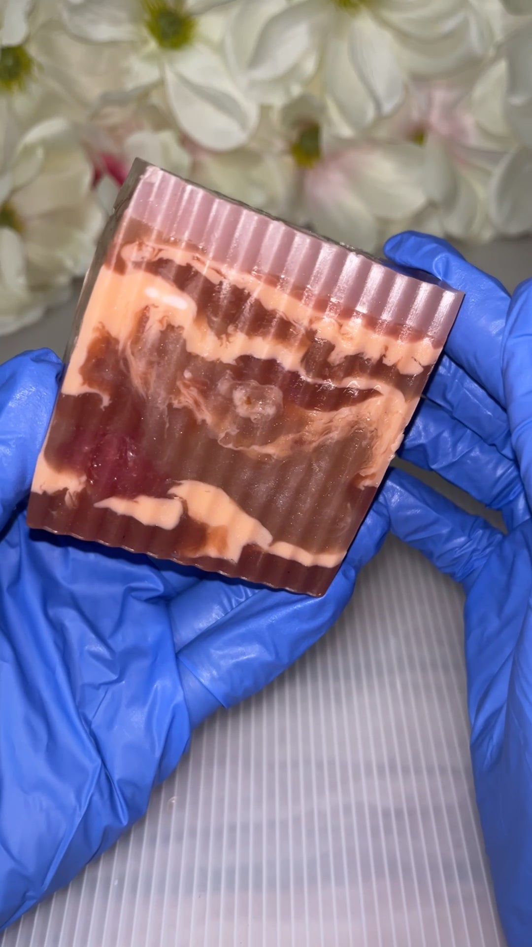 Hand with blue gloves holding a marble colored soap.